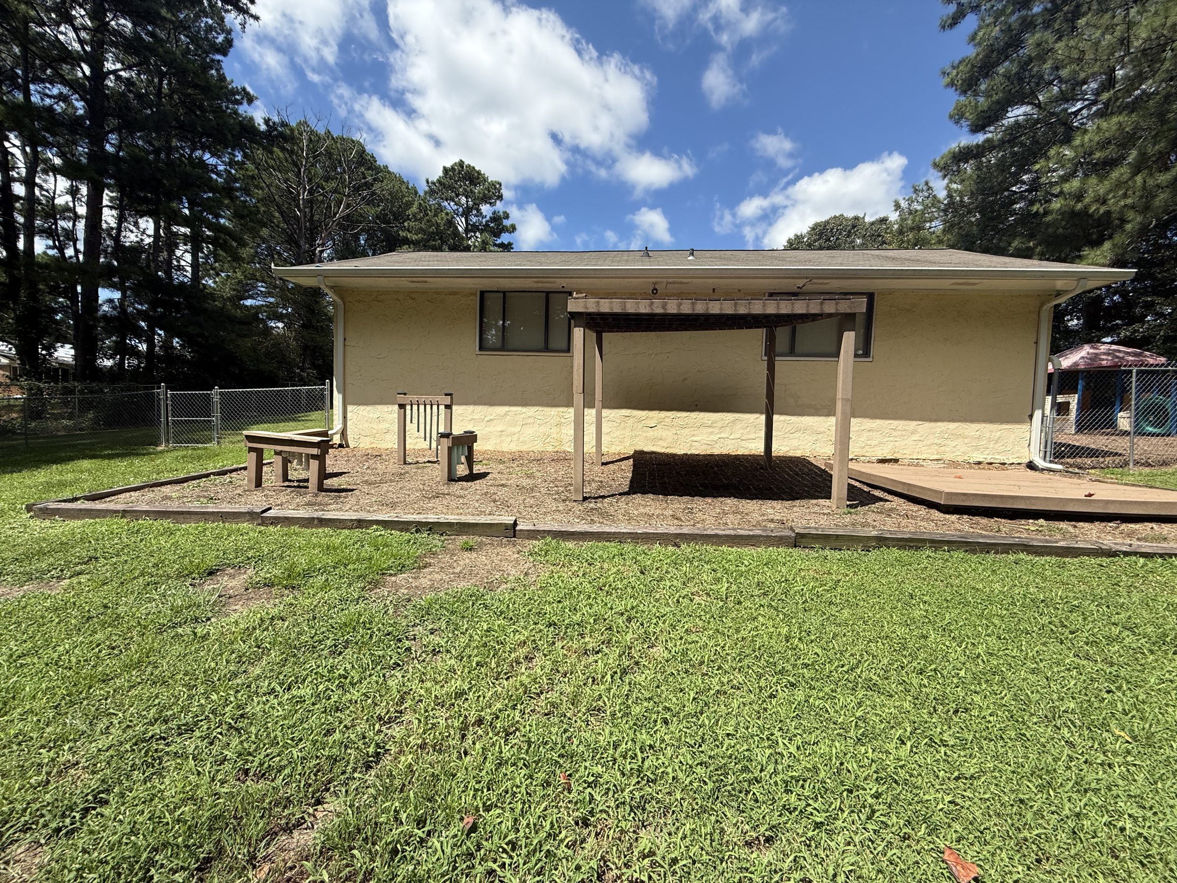 The Seven Oaks Academy school building and shaded outdoor play area under a blue sky