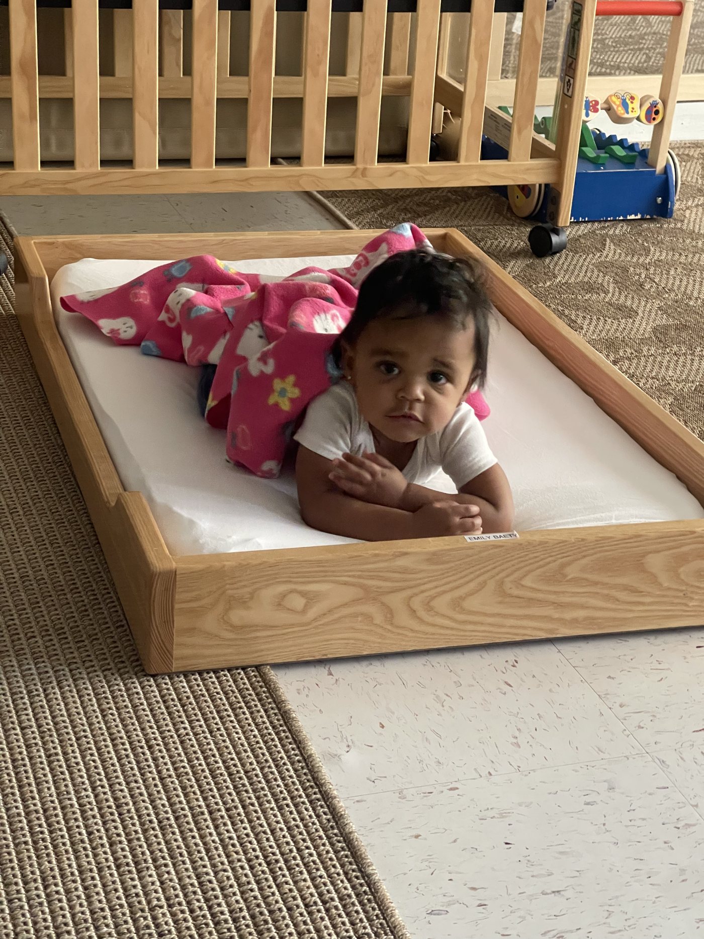 A Nido infant rests on a low floor bed in the classroom