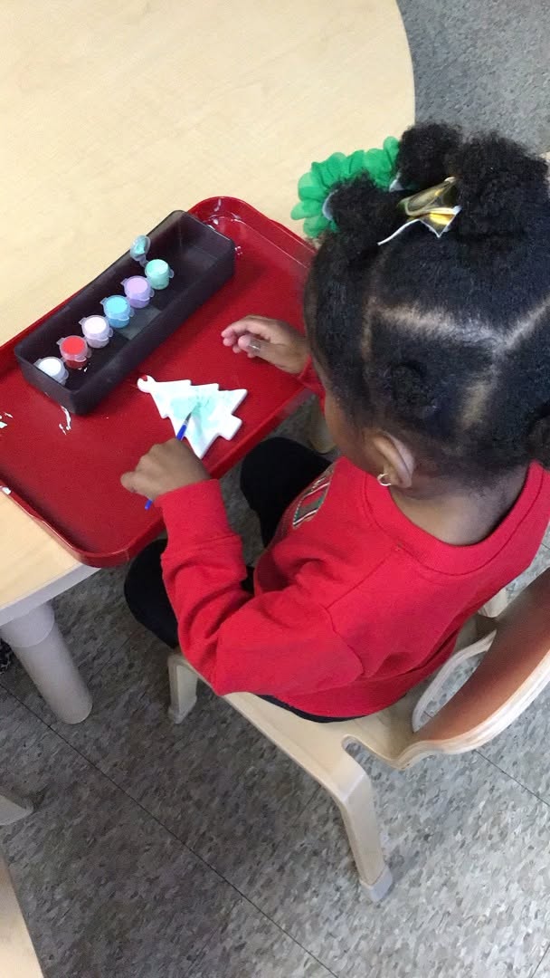 A Seven Oaks student paints a holiday ornament at her work table