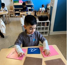 A Seven Oaks student traces a sandpaper letter during a language lesson