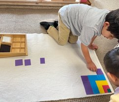 A Seven Oaks student works with Montessori bead materials on a floor rug