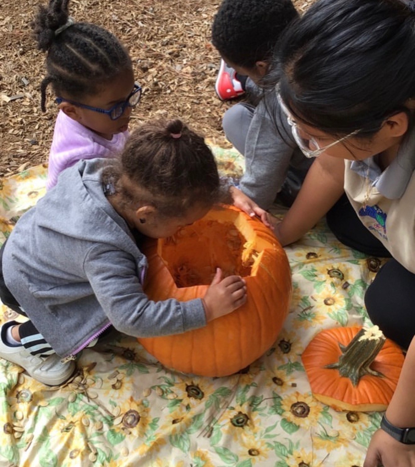 Seven Oaks students scoop out a pumpkin together with their teacher